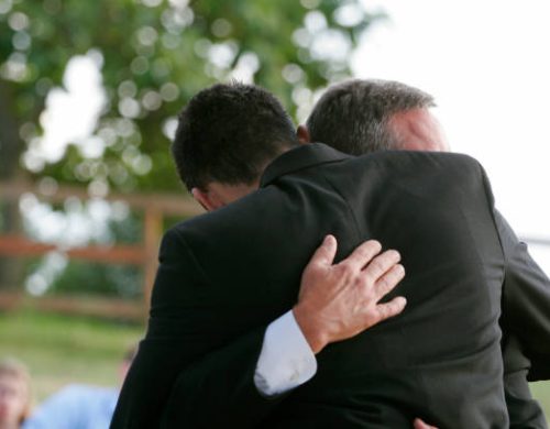 Two men hug each other.  Horizontal with copy space.